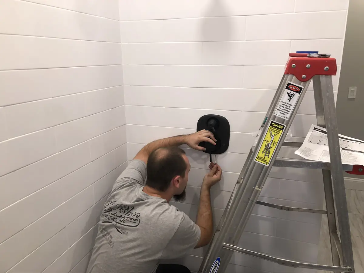 A.J. LeBlanc technician performing plumbing maintenance on a shower valve in New Hampshire