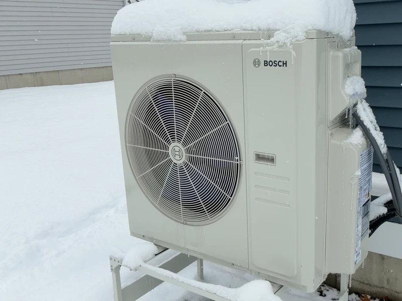 Bosch outdoor heat pump operating in winter with snow on the unit at a Southern NH home