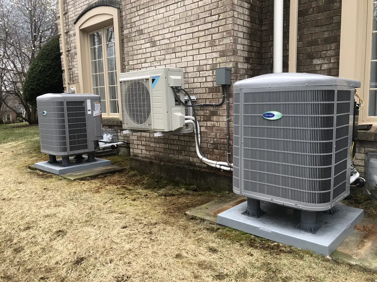 Heat pump condensers outside a New Hampshire brick home installed by A.J. LeBlanc Heating