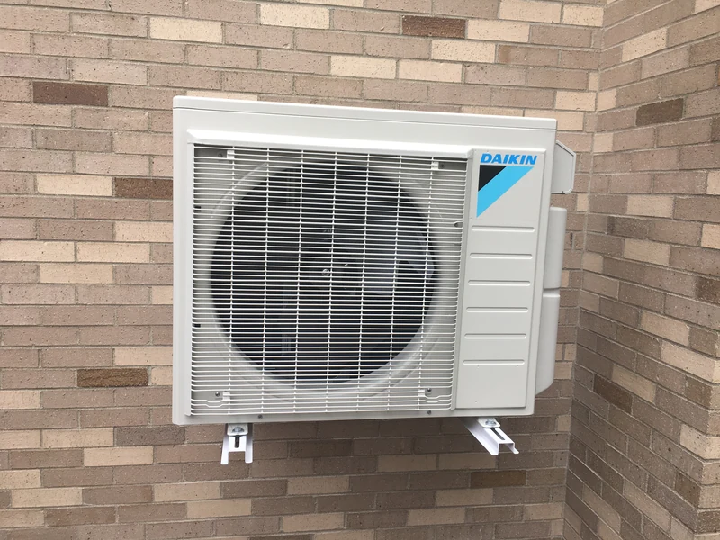 Daikin wall-mounted outdoor mini split on a brick wall in Southern NH