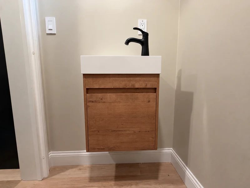Floating wood bathroom vanity with a white sink and matte-black faucet