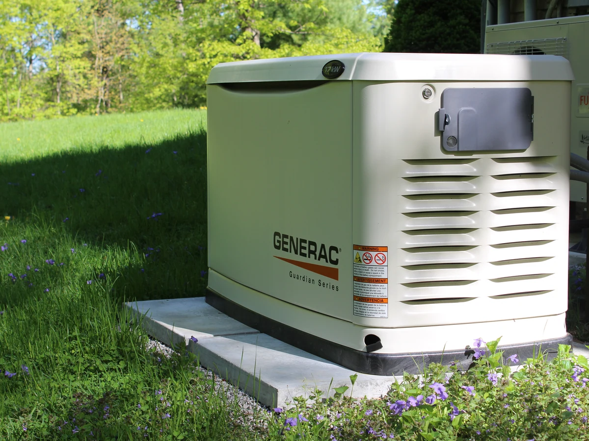 Generac standby generator on a gravel pad for comparison with whole-home battery backup options, installed by A.J. LeBlanc Heating in Southern NH