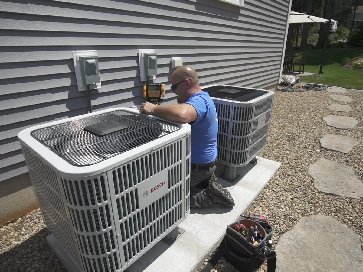 A.J. LeBlanc Heating technician servicing outdoor condenser units at a Southern NH home, the kind of installation eligible for financing through Wells Fargo Home Projects