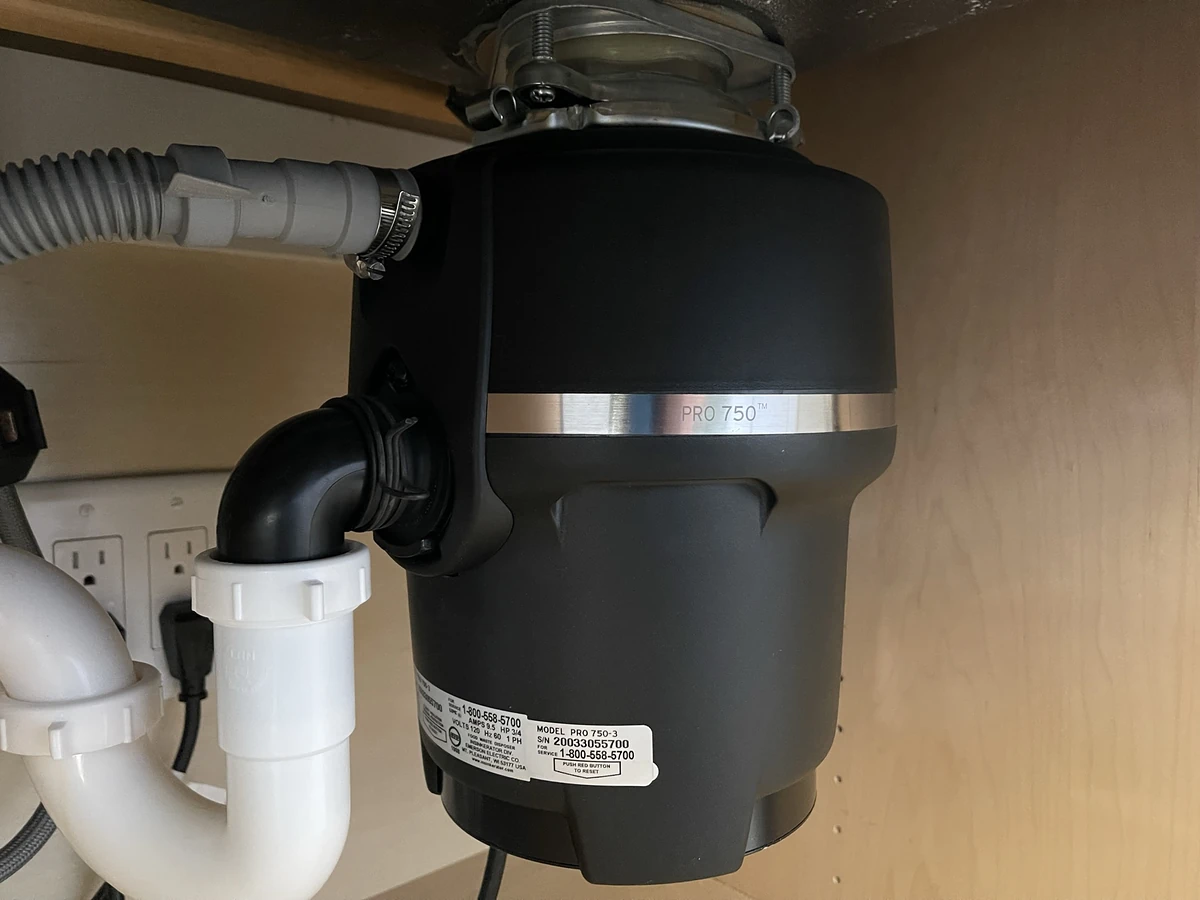 InSinkErator PRO 750 garbage disposal installed under a kitchen sink with PVC P-trap and dishwasher drain hose connection by A.J. LeBlanc Heating in Southern NH