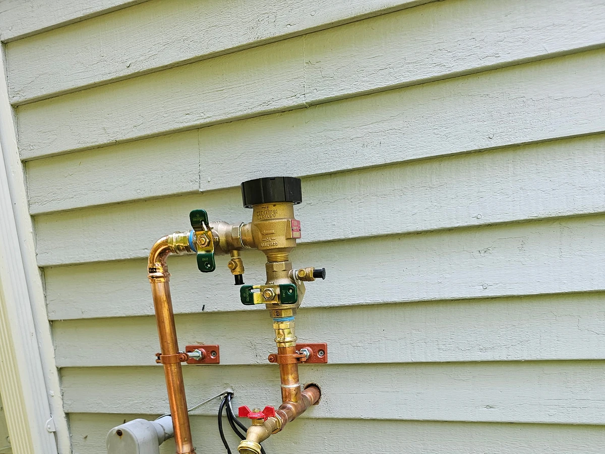 Exterior irrigation supply tap with a backflow preventer assembly installed by A.J. LeBlanc Heating at a Southern NH home