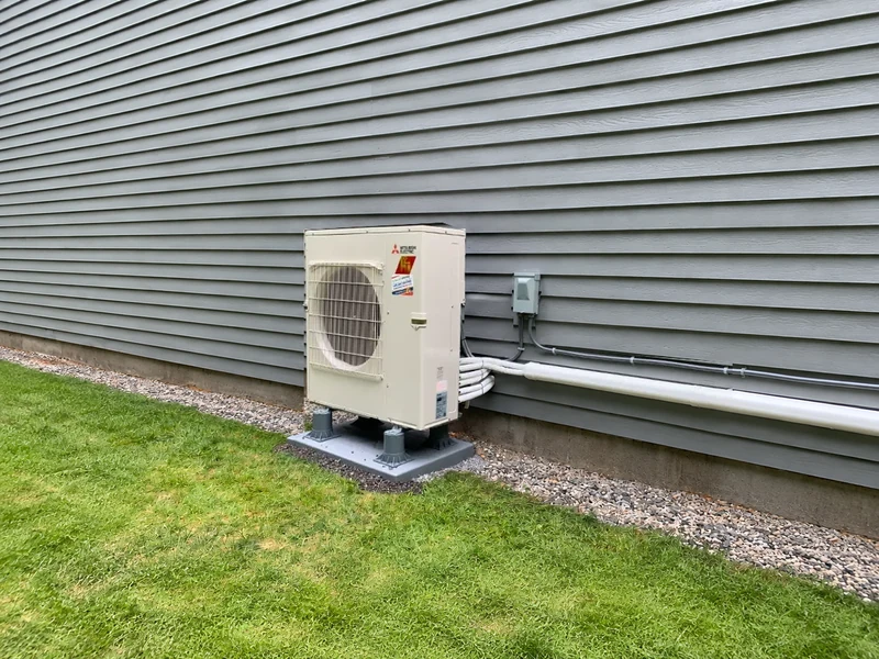 Mitsubishi Electric ductless mini split outdoor unit installed against gray siding at a Southern NH home