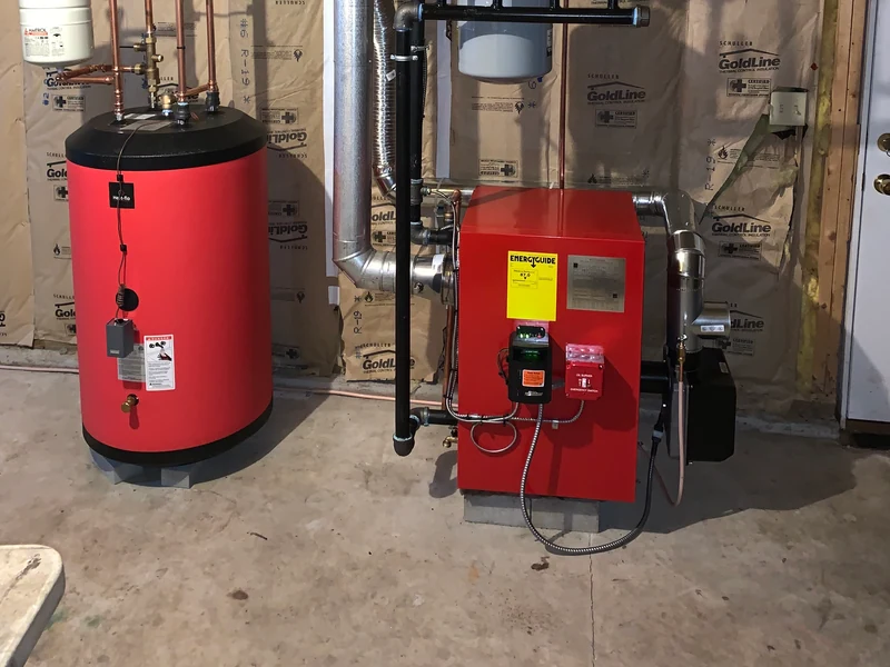 Red oil boiler with Beckett burner and matching red indirect water heater installed in a Southern NH basement