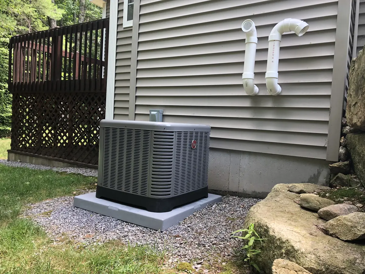 Rheem central air conditioner condenser on a gravel pad at a New Hampshire home