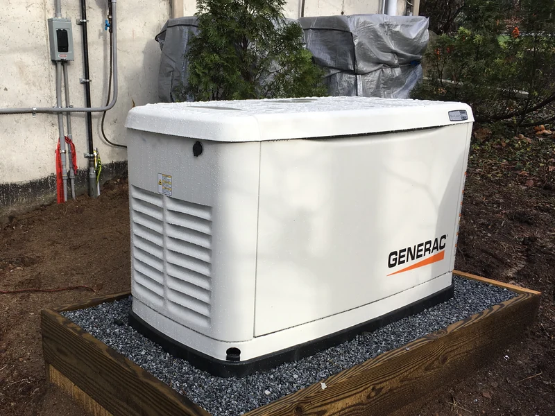 Air-cooled Generac whole-home standby generator installed on a wood-framed gravel pad against vinyl siding in Southern NH by A.J. LeBlanc Heating