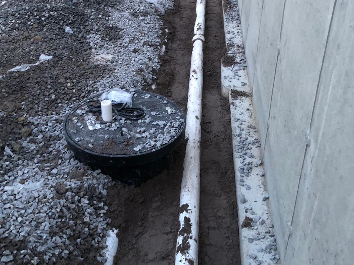 Residential sump pump and basin installed with discharge piping by A.J. LeBlanc Heating in a Southern NH basement