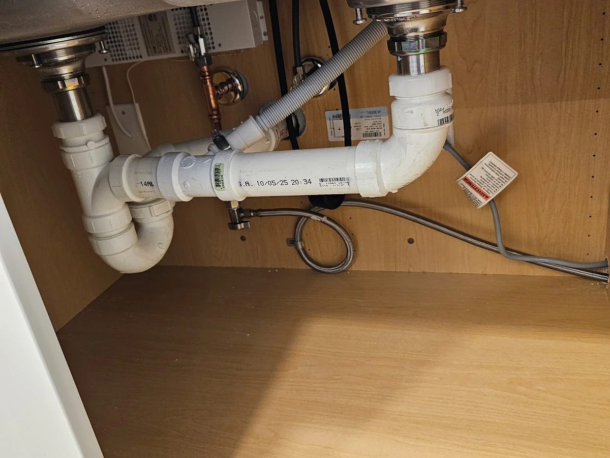 Under-sink plumbing repair with new PVC P-trap, basket strainers, and supply lines completed by A.J. LeBlanc Heating licensed plumbers in a Southern NH home