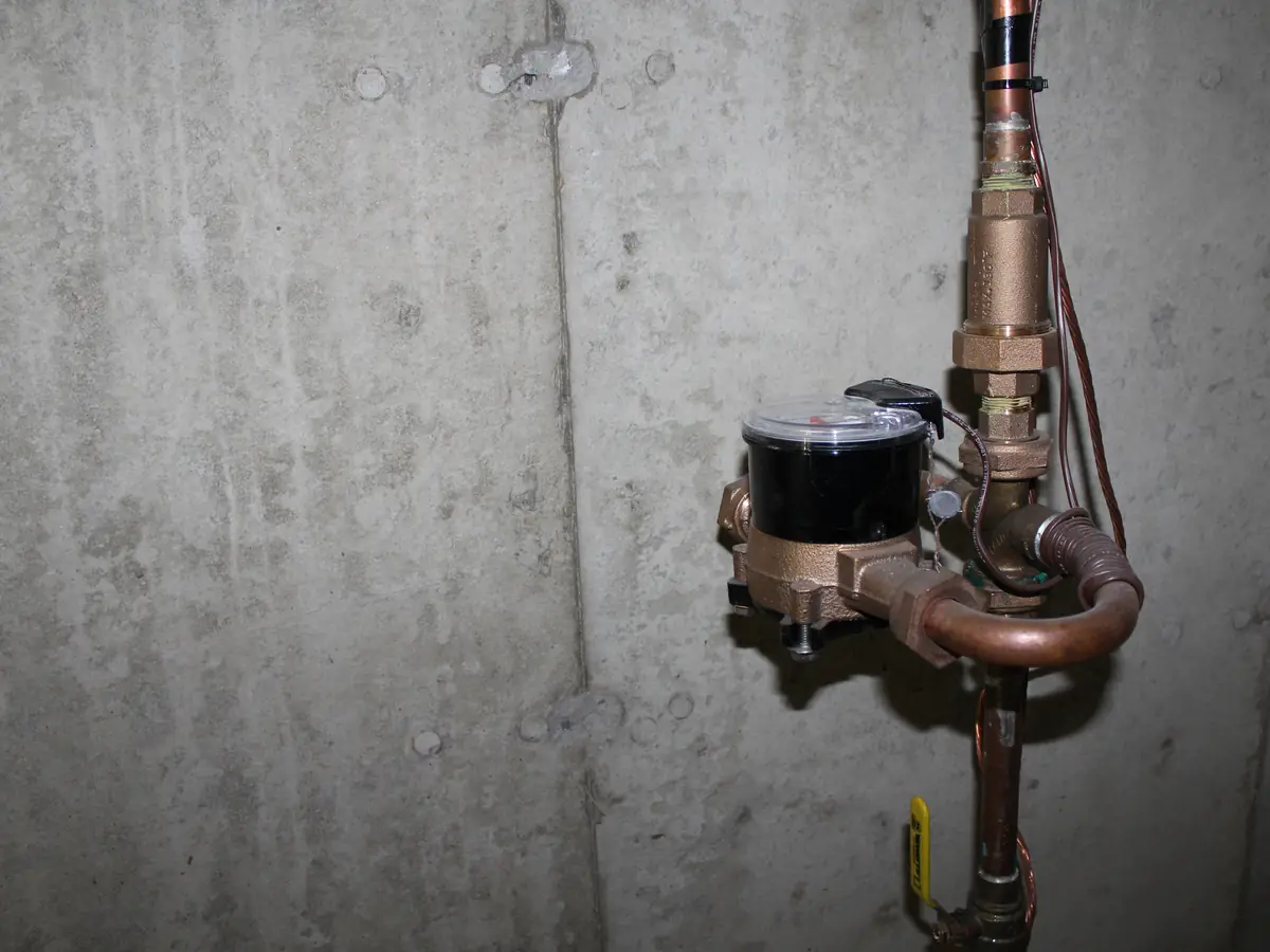 Residential water meter with copper plumbing service entrance inspected by A.J. LeBlanc Heating in a Southern NH basement